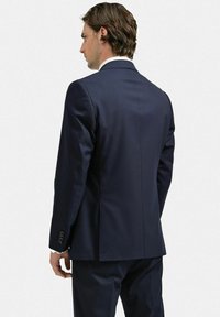 Mörkblå kostymjacka, slim fit, slät textur, enkel slits bak, fyra knappärmar, kontrasterande vit krageinsats.