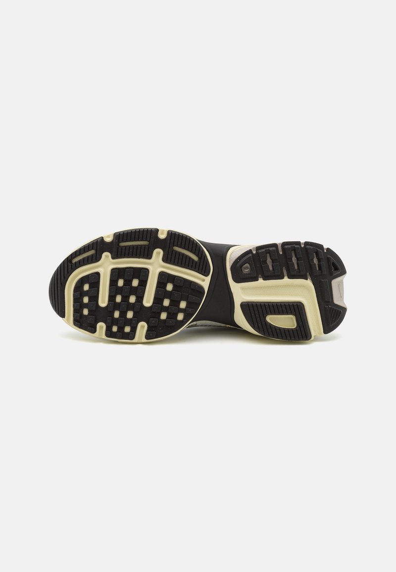 Suela de calzado deportivo con una base de goma negra texturizada, acentos en crema, zonas de agarre con patrón y un diseño moldeado para tracción y soporte.