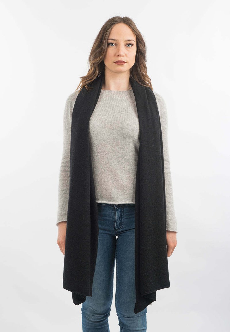 Sort uldesk scarf med blød tekstur, lang længde der hænger over en grå sweater, parret med blå jeans. Enkel design uden mønstre.