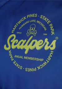 Tejido azul con un gráfico circular y texto verde. El texto incluye "Scalpers," un diseño de calavera y "Hartwick Pines - State Park."