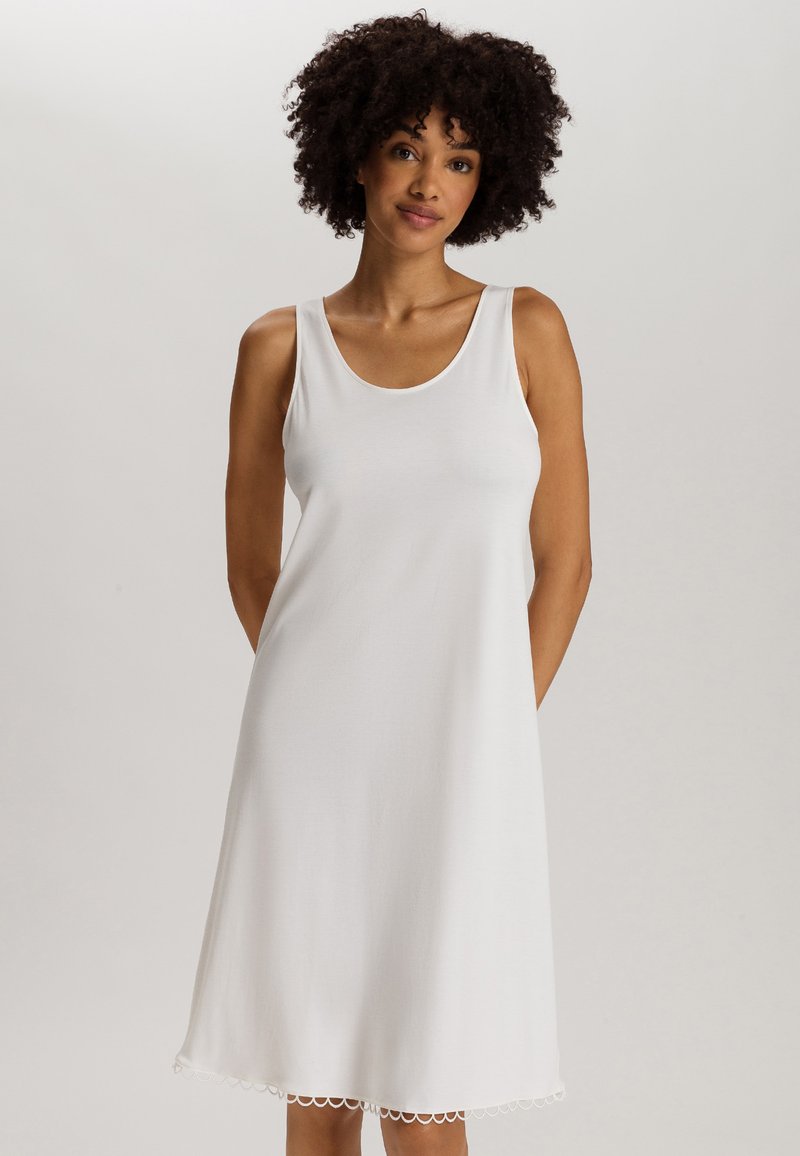 Vestido blanco sin mangas hecho de una tela suave, con un corte relajado y un dobladillo en forma de onda. Diseño simple, sin patrones ni embellishments.