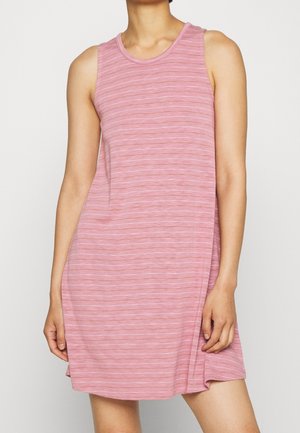 Robe rose sans manches, longueur genoux, avec de fines rayures horizontales blanches portée par une personne devant un fond uni.