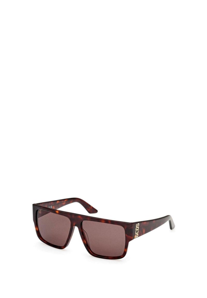 Gafas de sol marrón carey con lentes cuadrados, sutil degradado marrón y un acento de logo dorado en la patilla. Montura de plástico, diseño moderno.