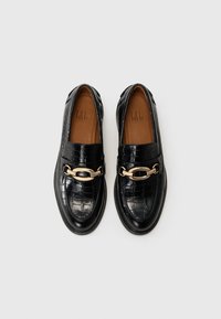 Sorte skinnloafers med krokodillemønster, med en gullkjede-accent over remmen og design med avrundet tå.