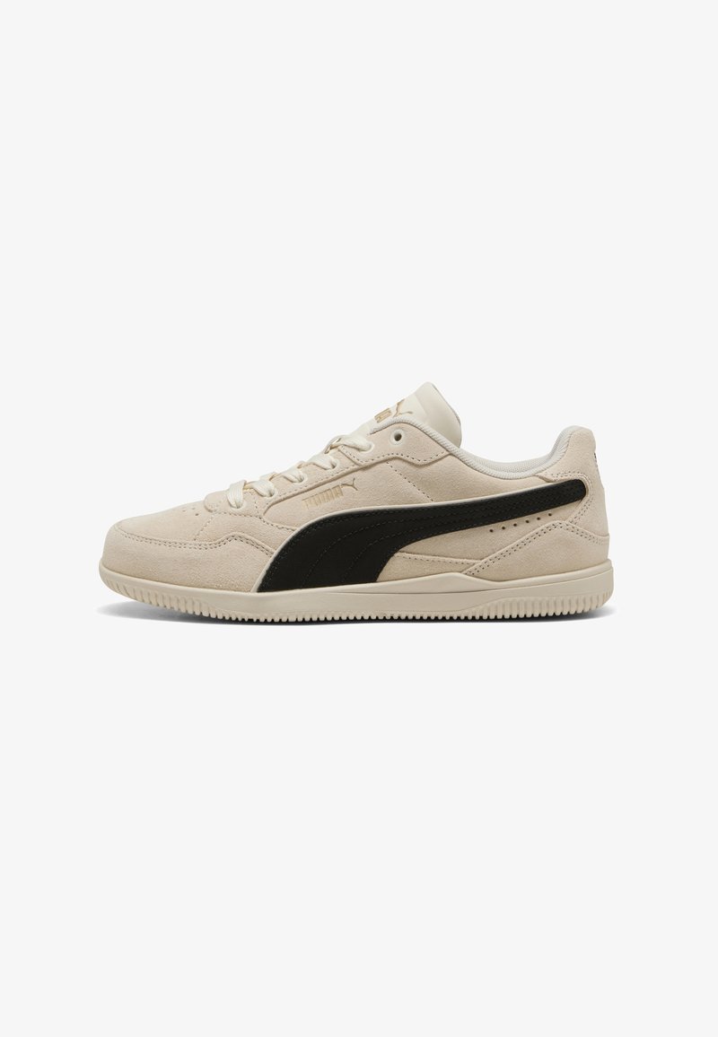 Baskets Puma en daim beige avec une rayure noire, design bas, fermeture à lacets et semelle en caoutchouc, vues de côté.
