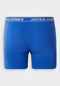 Modré pánské boxerky vyrobené z měkké tkaniny, s bílým elastickým pasem s potištěným logem "JACK & JONES". Hladká textura a úzký střih.