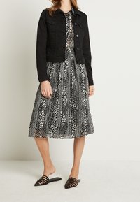 Svart denimjacka, blommig svartvit klänning, transparenta svarta sandlett med spetsiga tår och randig design.