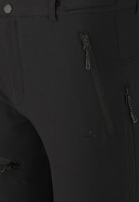 Svarta utomhusbyxor med dragkedjefickor och en strukturerad yta. Har subtil branding och en strömlinjeformad design för funktionalitet.