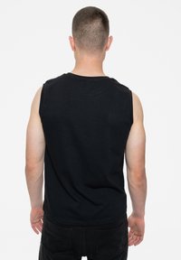 Black sleeveless cotton t-shirt with a round neckline, featuring a smooth texture and a simple design, viewed from the back.