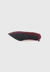 Escarpin à bout pointu en suède bordeaux foncé avec une semelle en caoutchouc noir. Présente un talon fin et une texture subtile sur le dessus.