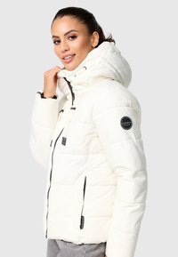 White puffer jacket with a hood. Features a quilted design, black zipper, adjustable drawstrings, and a round logo patch on the sleeve.