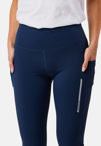 Granatowe legginsy sportowe z wysokim stanem, boczną kieszenią i odblaskowym akcentem. Gładki, elastyczny materiał z subtelnym detalem przeszycia.