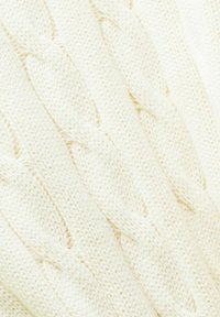 Tissu tricoté couleur crème avec un motif en torsades détaillé formant des textures tressées verticales.