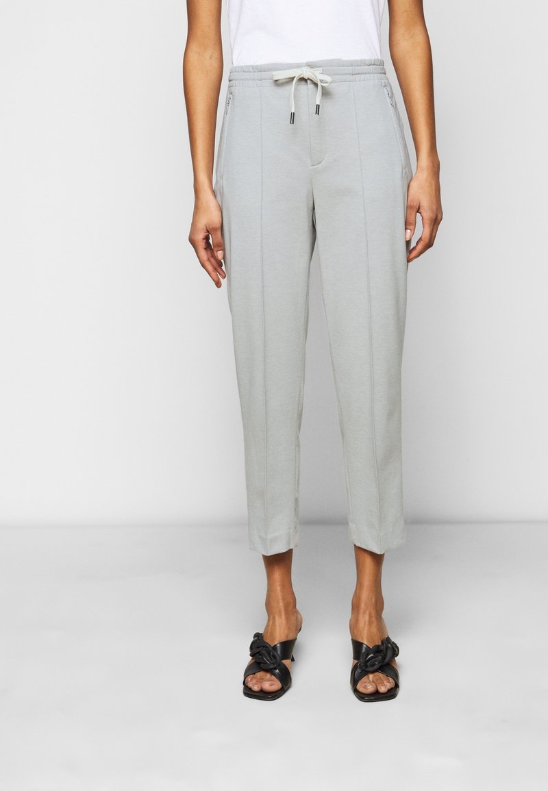 Pantalons jogger gris clair avec une taille élastique et un cordon de serrage, dotés de poches latérales et d'une conception de jambe fuselée.