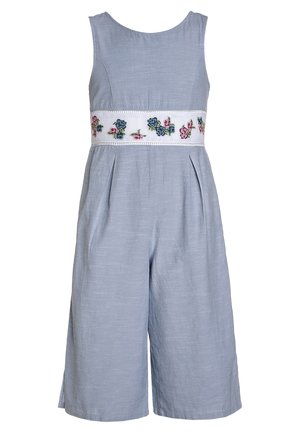 Mono de lino azul claro con cuerpo ajustado, pantalones anchos plisados y una cinturilla bordada con flores en rosa y azul sobre tela blanca.
