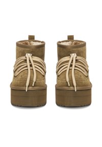 Pruunid nubukist pahkluu saapad tekstuurse viimistlusega, millel on paksud beežid paelad, ümar nina ja paks platvormitald. Pehme vooder on pealt nähtav.