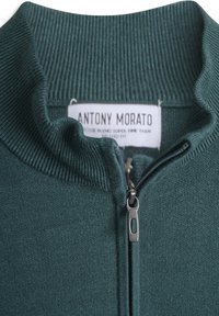 Sweater con zip verde scuro con collo a coste testurizzato, dotato di una cerniera argentata e un'etichetta con la dicitura "ANTONY MORATO" all'interno.