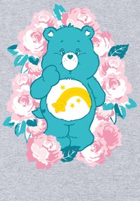 Niebieski miś z białym brzuchem, zdobiony żółtą tęczą i gwiazdką, otoczony różowymi różami i zielonymi liśćmi na szarym tle.