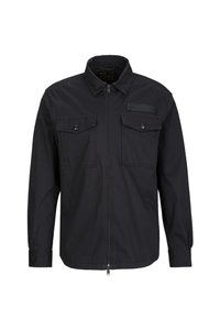 Schwarze Zip-Jacke mit spitzem Kragen, zwei Brusttaschen mit Knopfverschluss und einem strukturierten Etikett auf der oberen linken Seite.