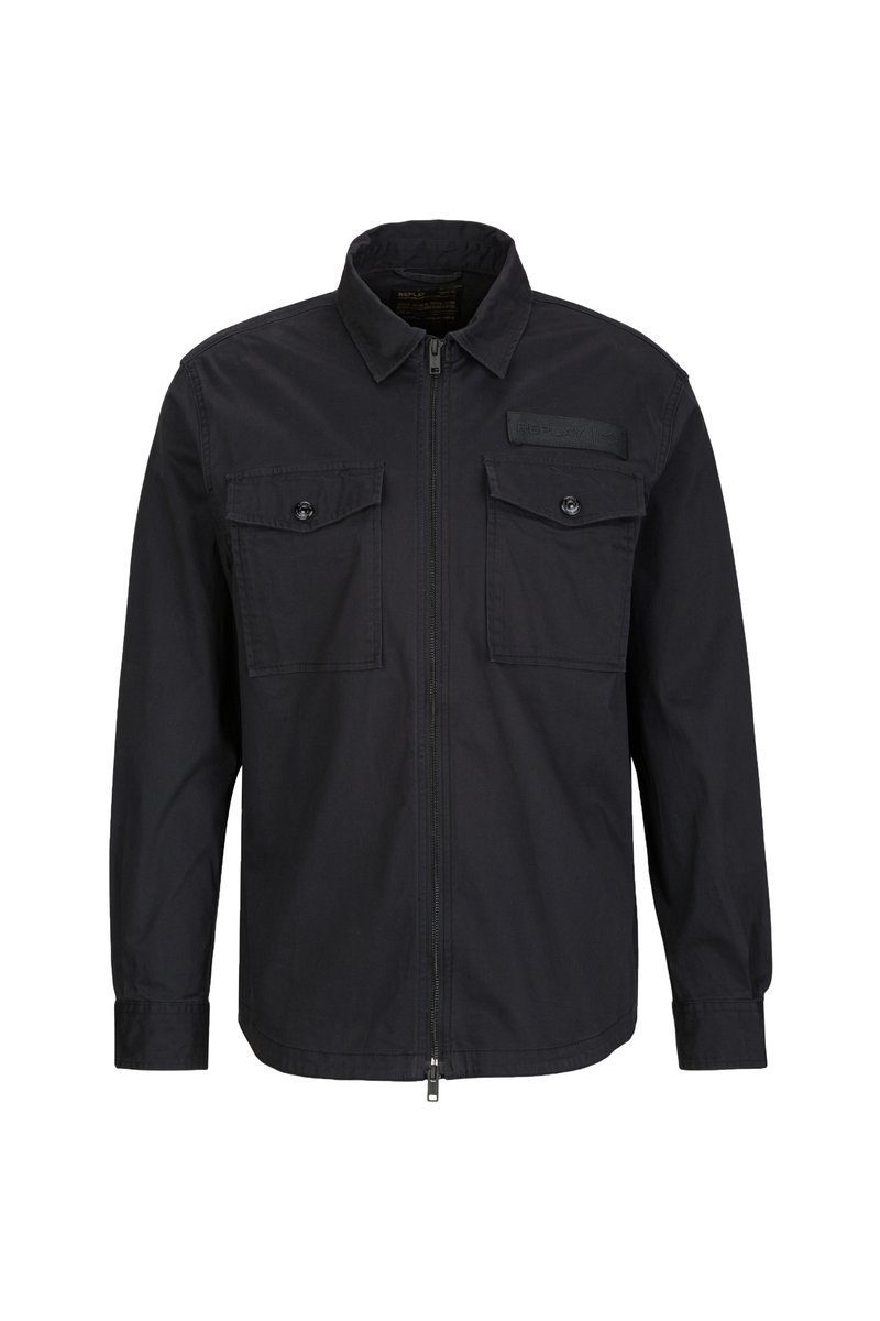 Schwarze Zip-Jacke mit spitzem Kragen, zwei Brusttaschen mit Knopfverschluss und einem strukturierten Etikett auf der oberen linken Seite.