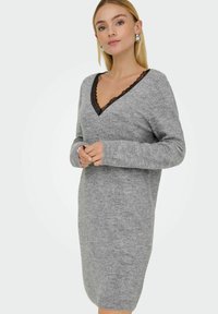 Vestido de punto gris con escote en V y ribete de encaje negro. Manga larga y diseño ajustado que llega justo por encima de las rodillas. Textura suave.