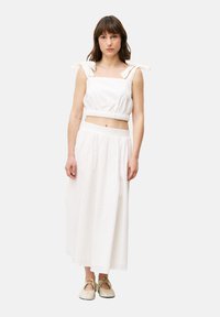 Witte twee-delige outfit bestaande uit een cropped top met strikbandjes en een lange, losse rok met een elastische taille. Zachte, gestructureerde stof.