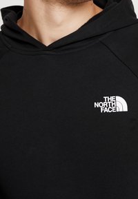 Felpa nera con scollatura a coste. Presenta il logo bianco de "The North Face" sul lato sinistro. Realizzata in tessuto morbido e texturizzato.