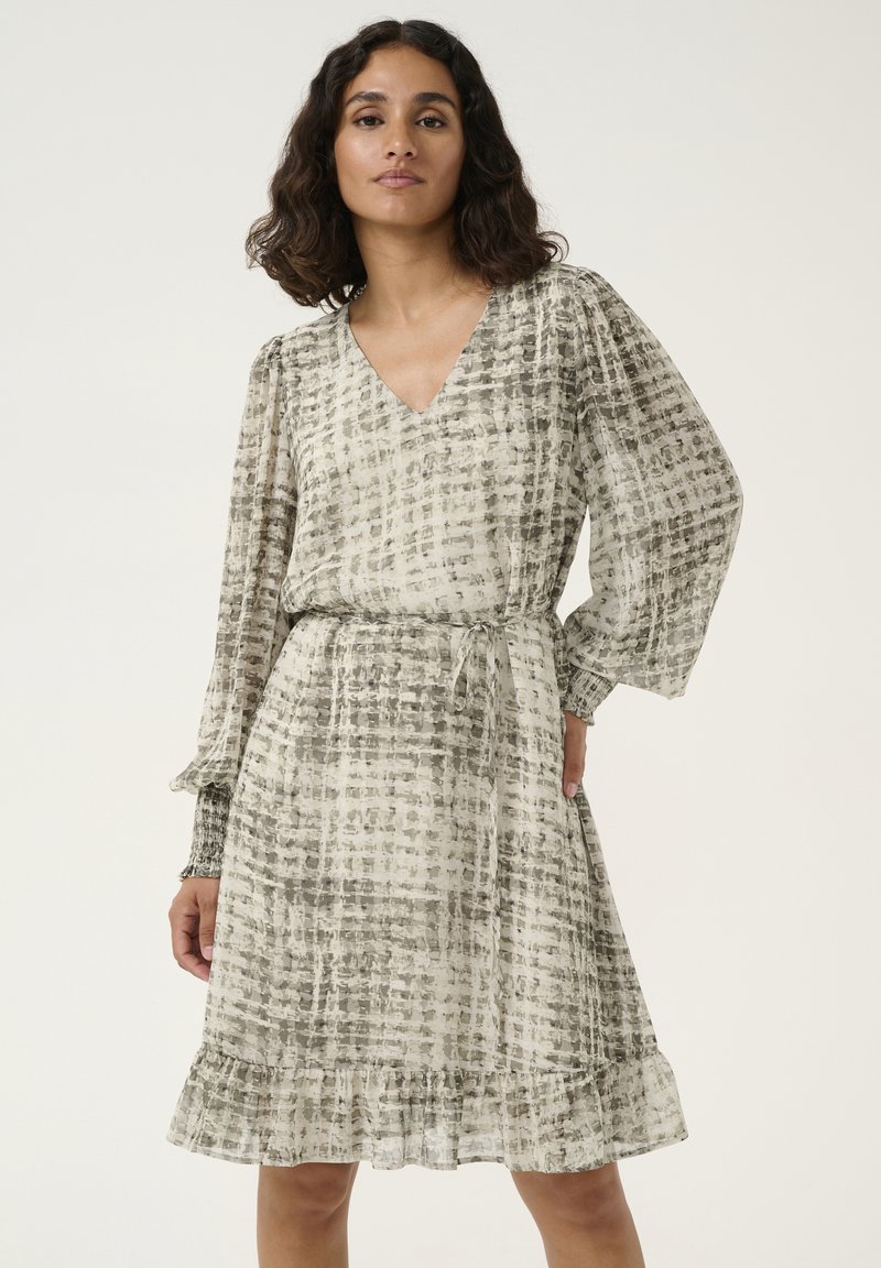 Robe légère avec un décolleté en V, de longues manches bouffantes et une taille ceinturée. Présente un motif à carreaux gris et crème et un ourlet à volants.
