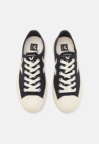 Navy canvas sneakers with white rubber soles and eyelets, featuring white laces and a contrasting logo on the tongue.