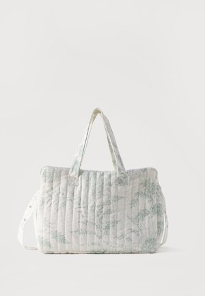 Borsa a tracolla trapuntata bianca con stampa botanica verde pallido, manici corti doppi e tracolla laterale regolabile su sfondo semplice.