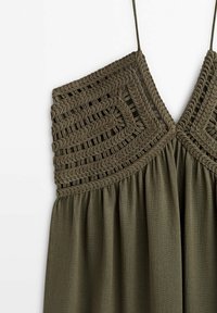 Haut sans manches vert olive avec détail en macramé tressé sur la poitrine et fines bretelles.