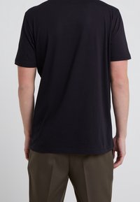 Zwart katoenen T-shirt met korte mouwen, ronde hals en een losse pasvorm. De achterkant is glad zonder zichtbare logo's of patronen.