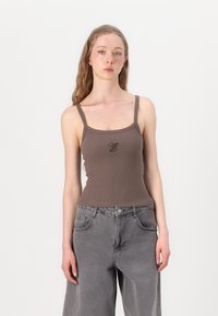 Brun ribbet topp med firkantet utringning og tynne stropper. Har et lite svart grafisk design på forsiden. Bært sammen med grå vide jeans.