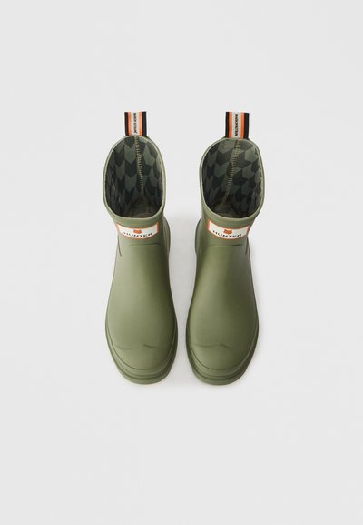 Botas de borracha verdes até ao tornozelo com um exterior liso, um forro de tecido estampado e uma alça na parte de trás para facilitar o calçar.