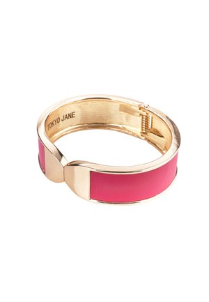 Armbanduhr in Goldfarbe mit einem pinkfarbenen Lederband, glatter Oberfläche und einem Verschlussdetail, auf der Innenseite mit "TOKYO JANE" versehen.