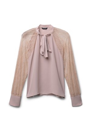 Blusa beige a maniche lunghe con maniche in pizzo trasparente, colletto alto e dettaglio di fiocco legato sul davanti.