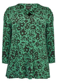 Green floral-patterned top with a V-neck, long sleeves, and black flower accents. The fabric appears soft with a relaxed fit.
