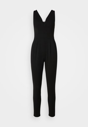 Tuta nera con scollatura a V, corpino aderente e gambe affusolate. Realizzata in materiale elasticizzato con zip sul retro per la chiusura.