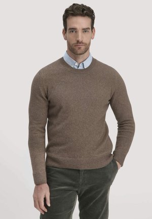 Brauner Pullover mit Rundhalsausschnitt und gerippten Bündchen, über einem hellblauen Hemd mit Kragen getragen. Das Material wirkt weich mit einer dezenten Textur.