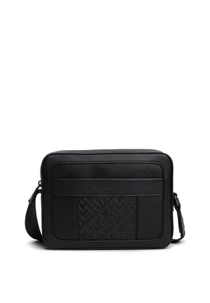 Sac bandoulière rectangulaire noir avec panneaux avant texturés et motif géométrique en relief, sangle ajustable, et marque "Tommy Hilfiger".