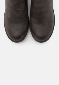 Botas negras hasta el tobillo hechas de cuero suave con punta redondeada y diseño minimalista. La suela es ligeramente elevada para mayor comodidad.