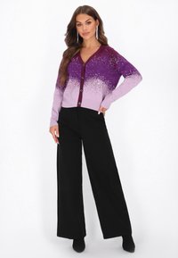 Cardigan cu gradient purpuriu și embellishments strălucitoare, având un guler în V, închidere cu butoane și mâneci lungi, asociat cu pantaloni negri cu croială largă.