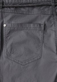 Pantalones de algodón gris con un bolsillo trasero que presenta costuras curvas, un remache de metal y una textura suave. Diseño minimalista, forma entallada.