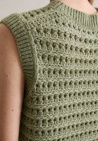 Gebreide vest in lichtgroen met een getextureerd opengewerkt patroon, ribbelkraag en mouwloos ontwerp, vervaardigd uit een zacht wolachtig materiaal.