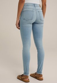 Ljusblå skinny jeans med hög midja, som har två bakfickor och en slät yta. Matchat med bruna sandaler.