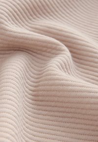 Šviesiai rožinės spalvos ribuotas audinys su subtilia tekstūra, kurioje tolygiai išdėstyti vertikalūs brūkšniai ir minkšta, jauki išvaizda.