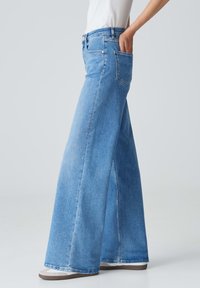 Jeans a gamba larga blu chiaro realizzati in denim, con vita alta, tasche frontali e posteriori, e una vestibilità rilassata con una leggera svasatura nelle gambe.