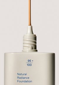 Base de Maquillaje Natural Radiance en un envase blanco suave con textura mate, con una boquilla giratoria y texto azul que indica el tono y el nombre del producto.