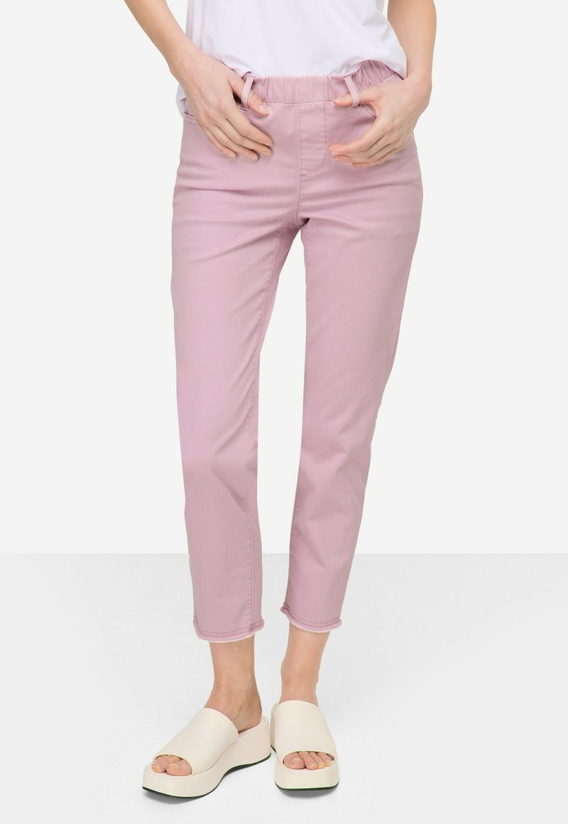 Pantaloni cropped rosa con vita elastica e cordoncino. Presentano tasche laterali e orlo arrotolato. Abbinati a sandali con plateau color crema.