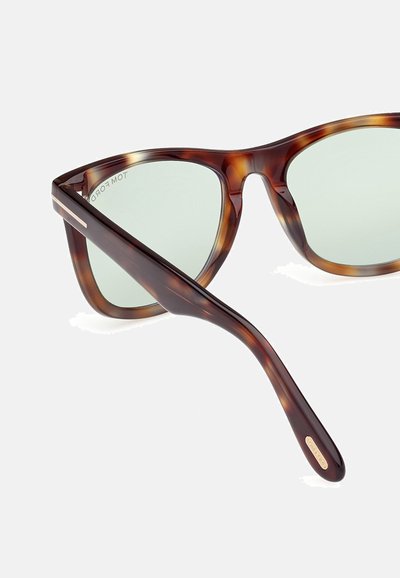 Ochelari de soare tortoise cu un cadru geometric, lentile de culoare verde deschis și accente metalice subțiri, cu o textură netedă din plastic.